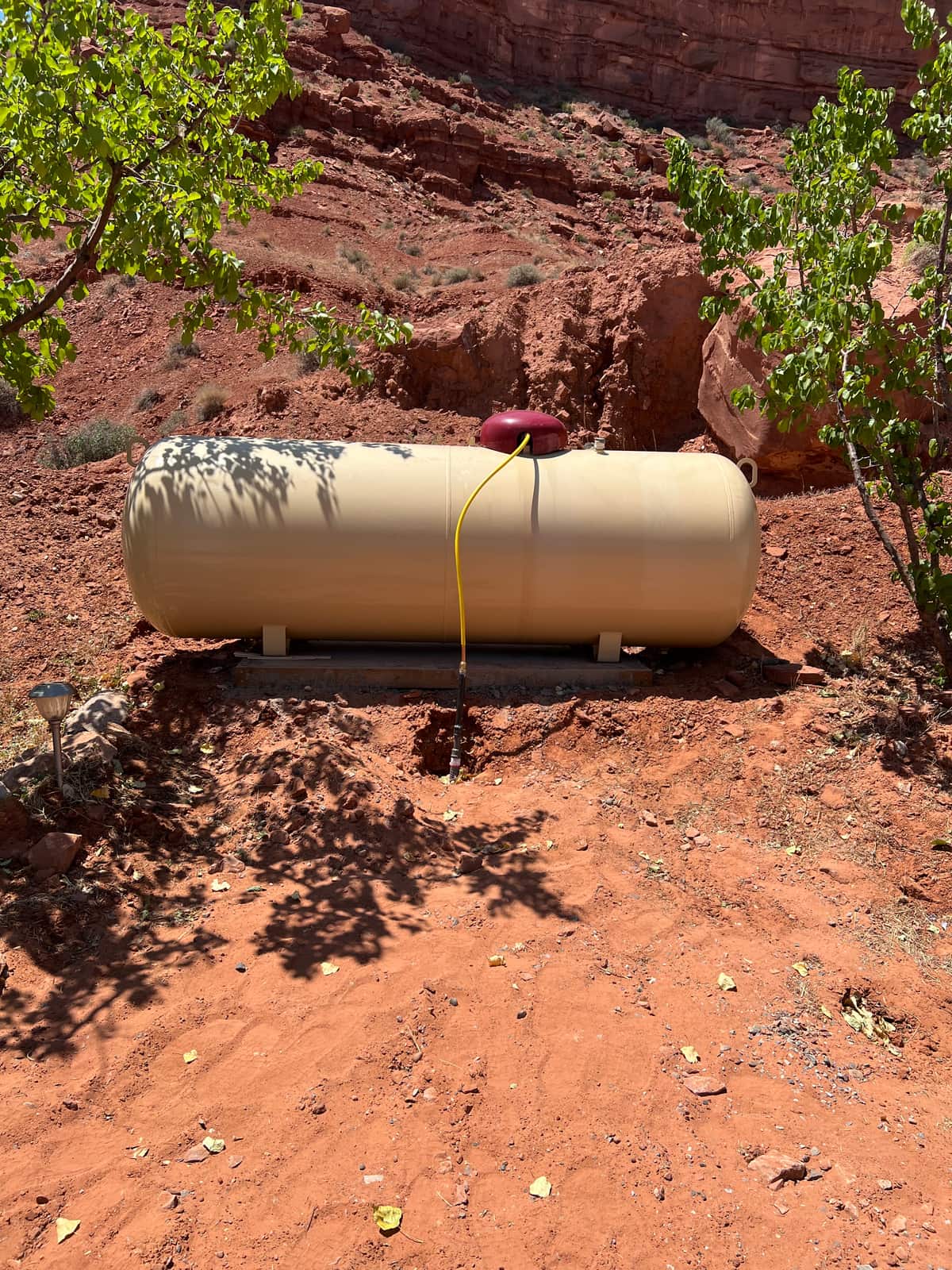 A propane tank set beneath red rock canyon terrain, part of Running Horse Services' territory.