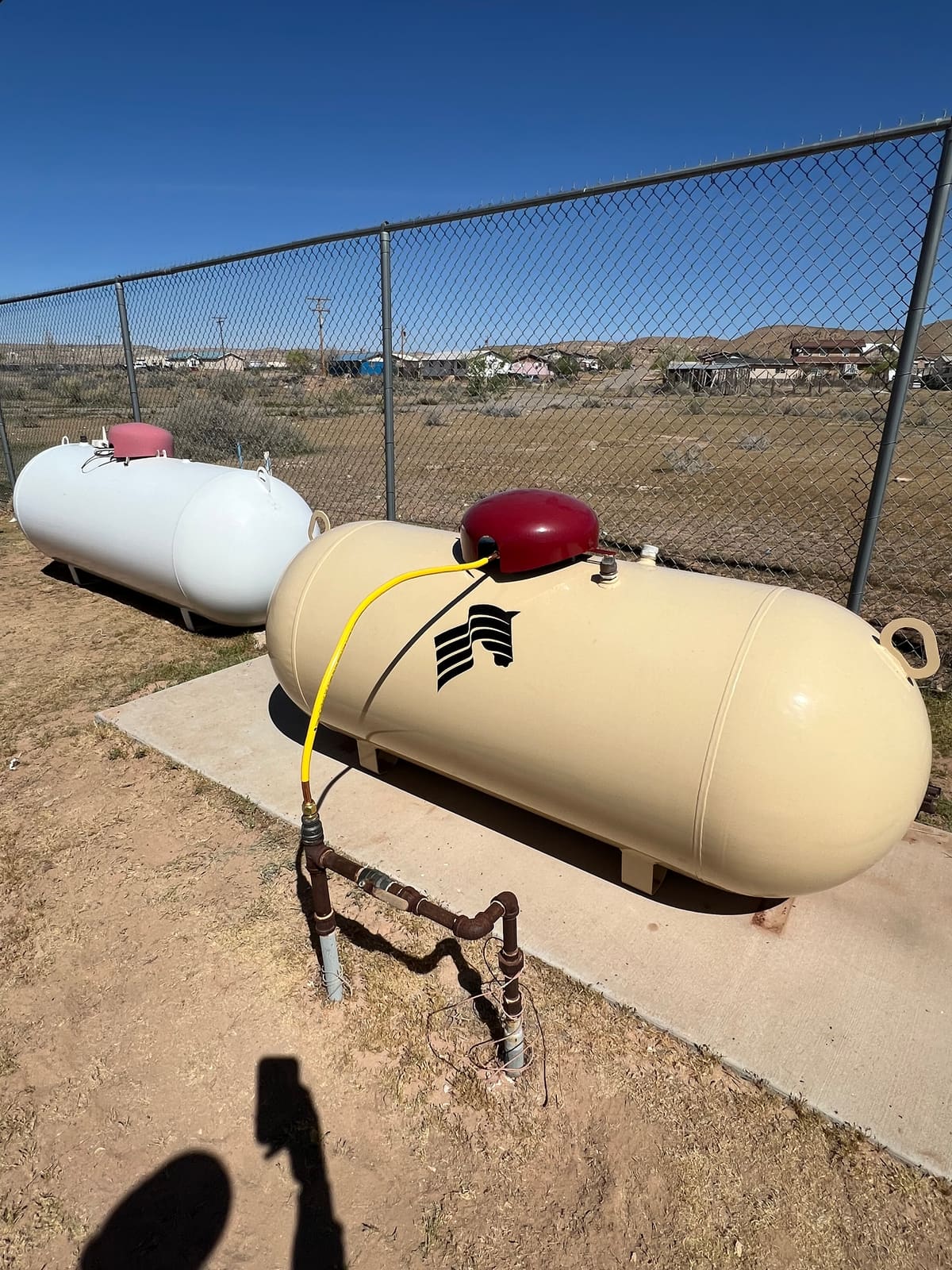 Propane tanks staged at the Running Horse Services yard behind a chain-link fence.